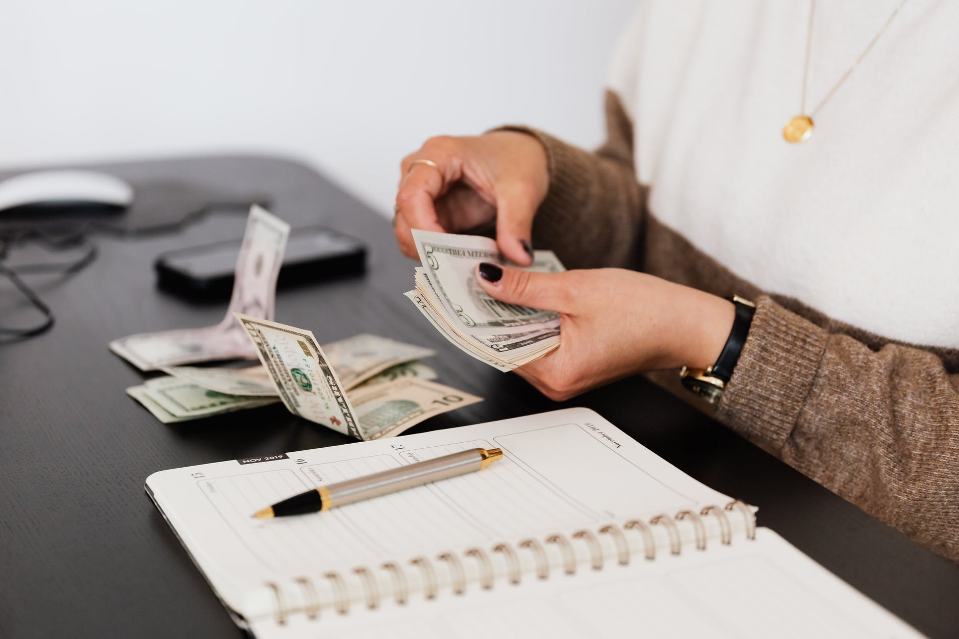 crop payroll clerk counting money while sitting at table